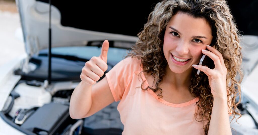 Woman on phone in front of car, contemplating full coverage insurance options.