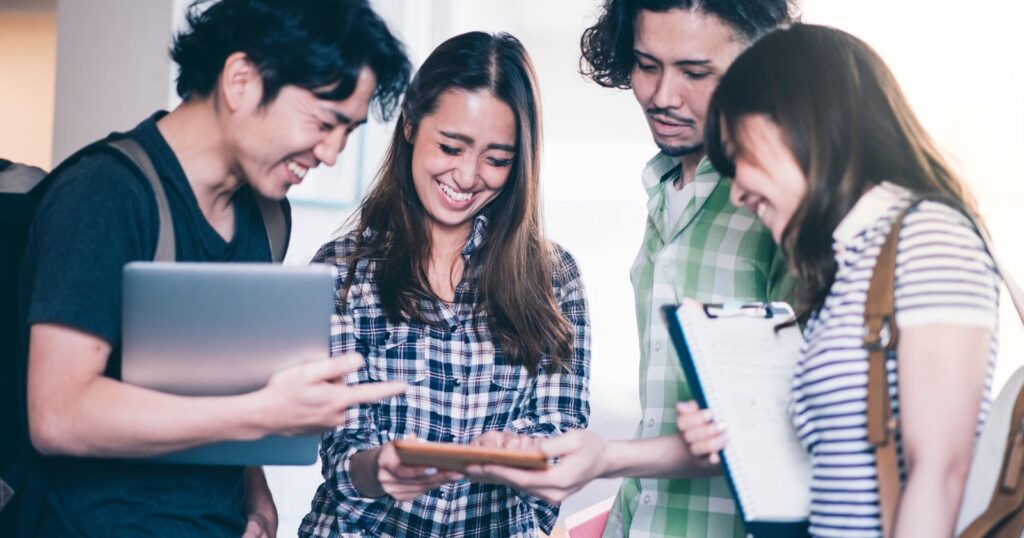Four young people looking at a tablet computer, engaged in 'Advancing Your Career with the GED'.